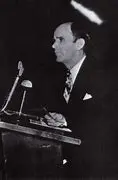 Man speaking at a podium, black-and-white photo.