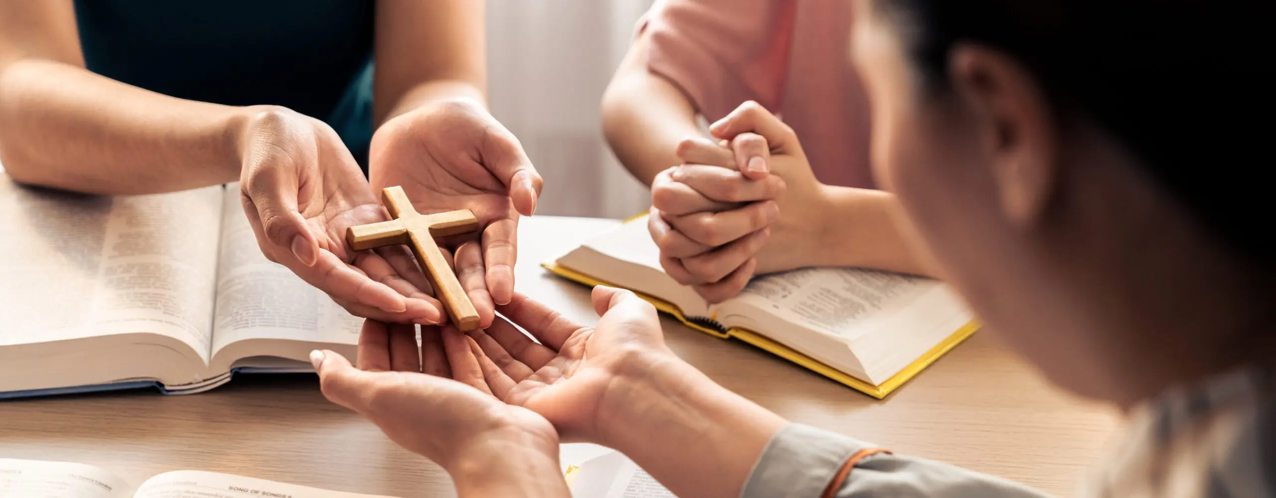 People holding cross and praying with books.