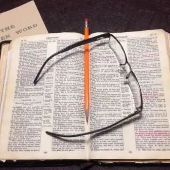 Open book with glasses and pencil.