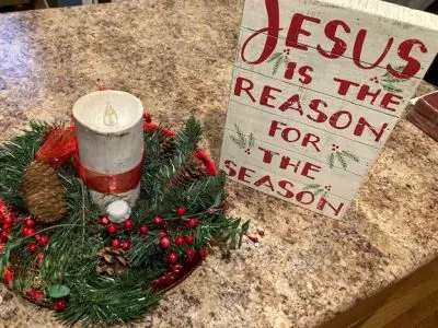 Christmas decor with candle and festive sign.