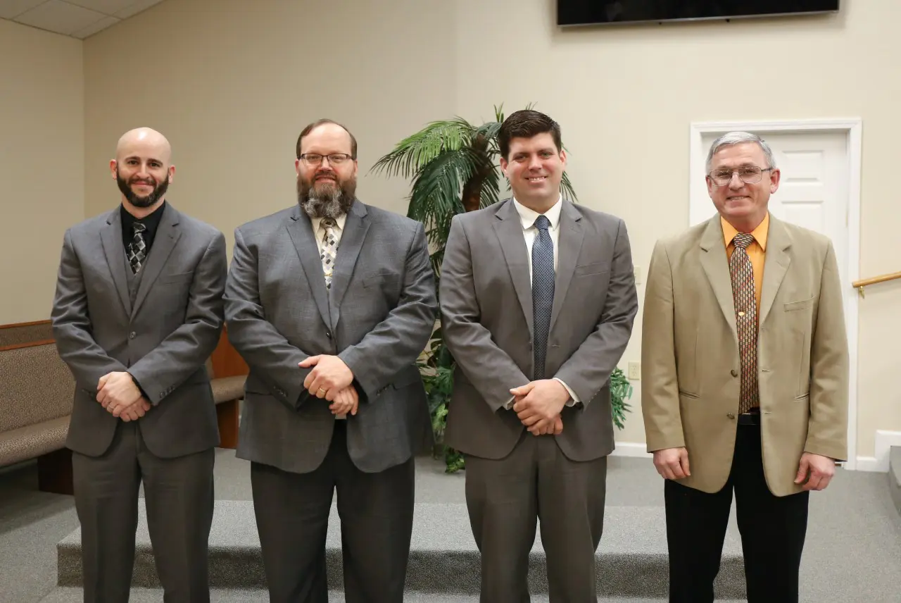 Four men in suits standing together indoors.