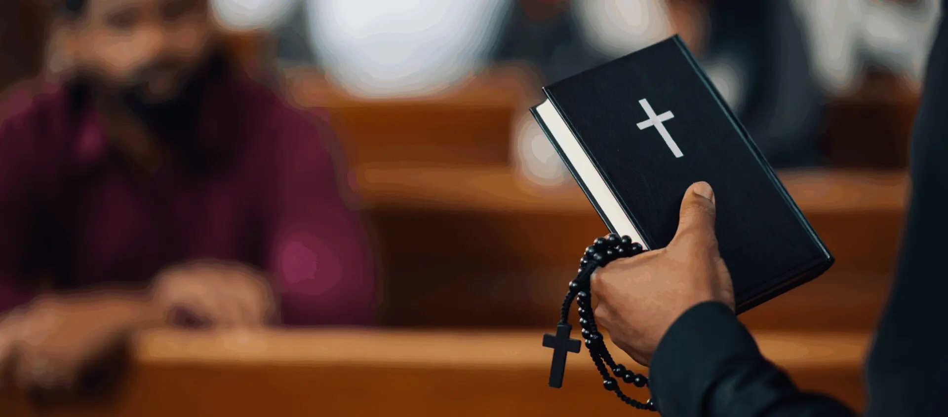 Priest holding Bible and rosary beads.