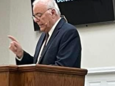 Man speaking at a podium indoors.