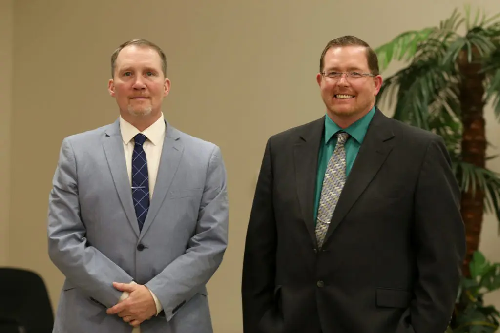 Two men standing in formal attire indoors.