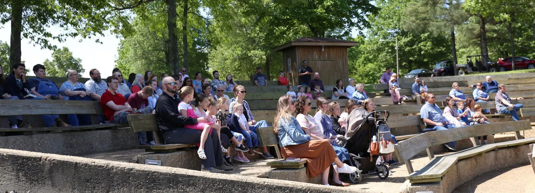 Families seated at outdoor park amphitheater