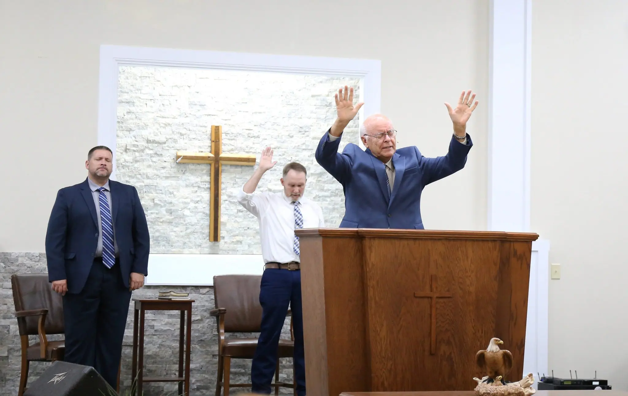 Pastor preaching at pulpit with cross backdrop