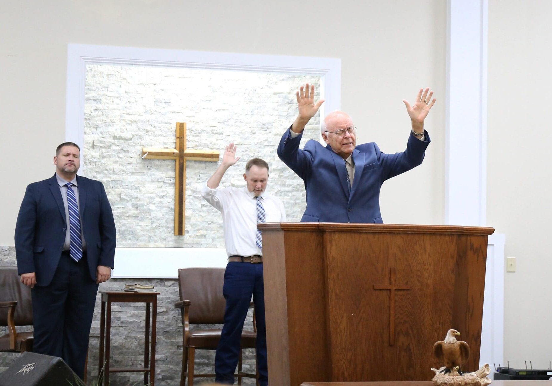 Pastor preaching at pulpit with cross backdrop
