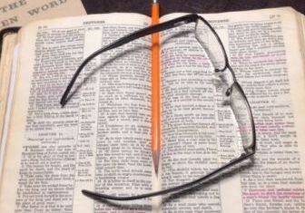Open book with glasses and pencil.