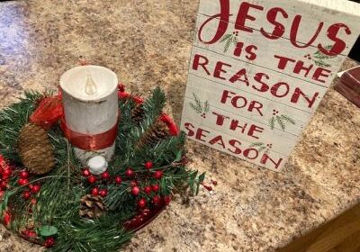 Christmas decor with candle and festive sign.