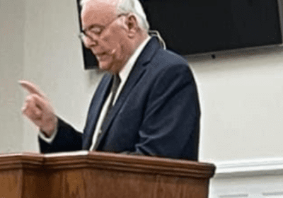 Man speaking at a podium indoors.