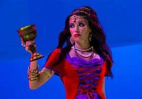 Woman in costume holding ornate goblet.